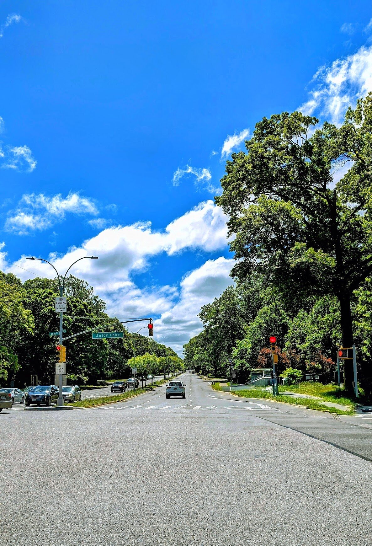 Suburban street under a bright blue sky with scattered clouds