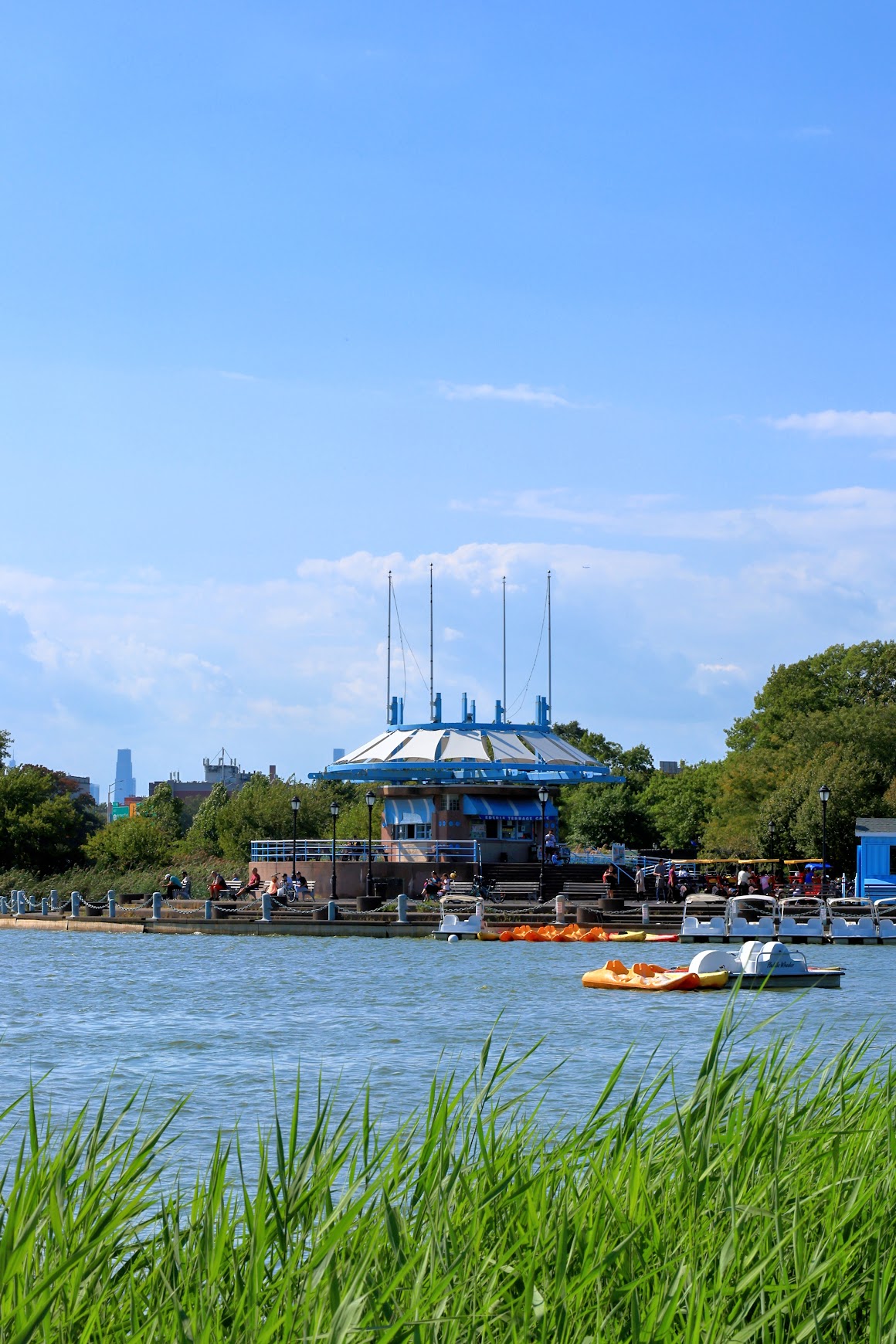 Park pavilion and pedal boats on a lake framed by green grass