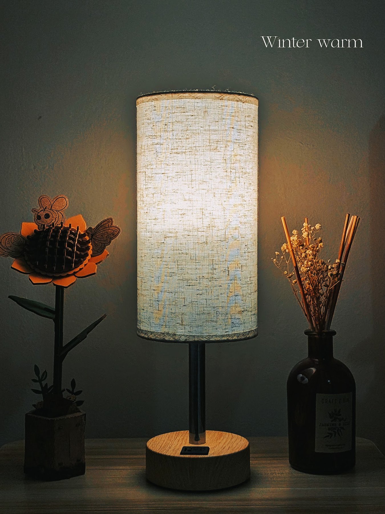 Cozy table lamp glowing warmly beside dried flowers and handmade paper decor