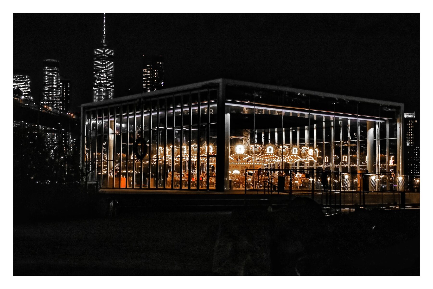Glass restaurant building lit up against the city skyline at night
