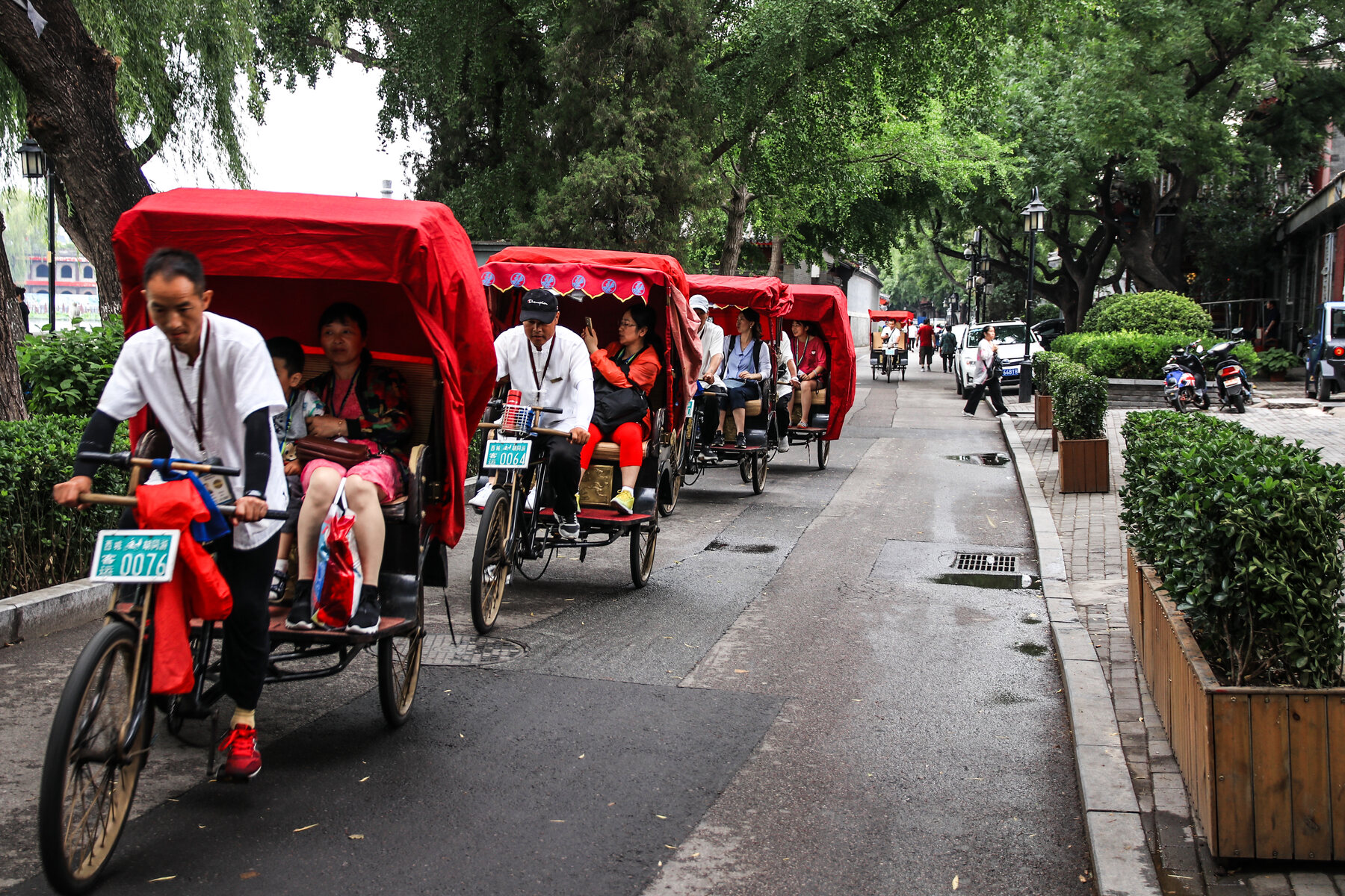 Pedicabs riding down a tree-lined street in Beijing