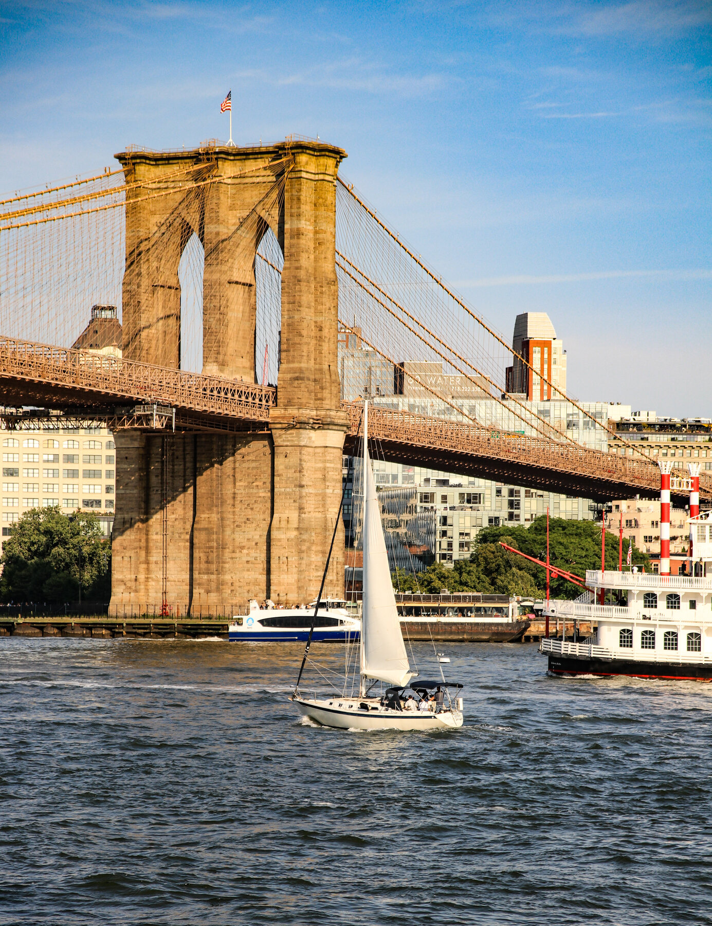 Brooklyn Bridge with a sailboat passing underneath