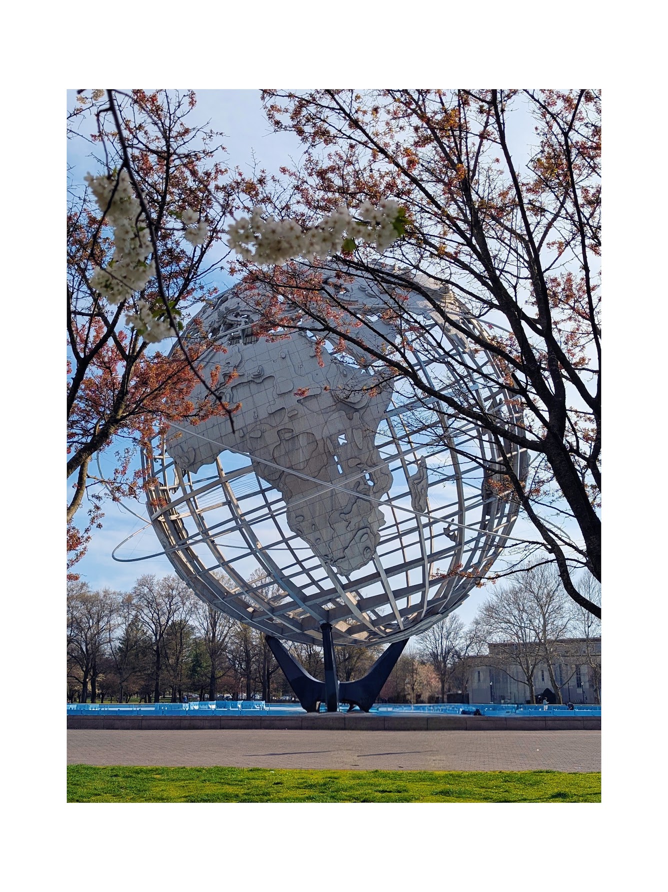 The Unisphere at Flushing Meadows Corona Park framed by cherry blossom branches